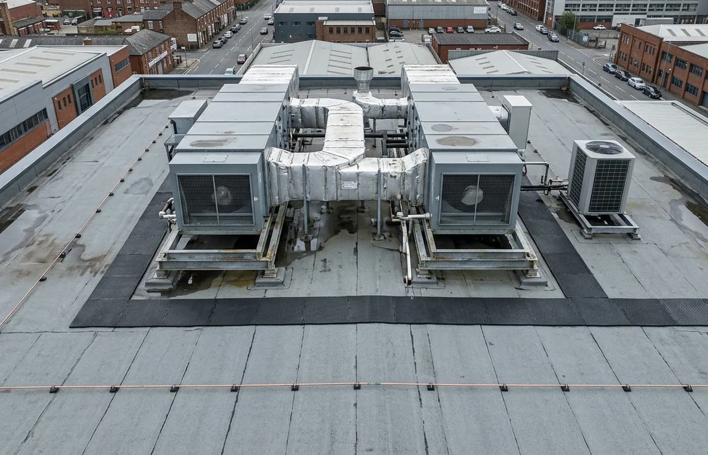 Rooftop plant on a flat commercial roof with air handling units, ductwork and a walkway route, photographed from directly above